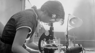 A woman looks into a microscope. 